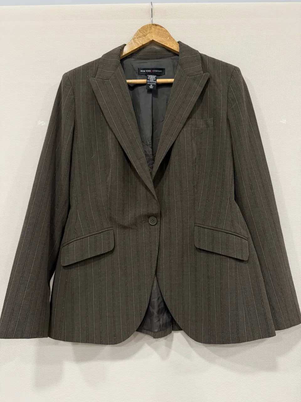 Blazer de vestir gris con finas rayas verticales blancas y detalles metalizados. Ideal para un look formal o de trabajo.
