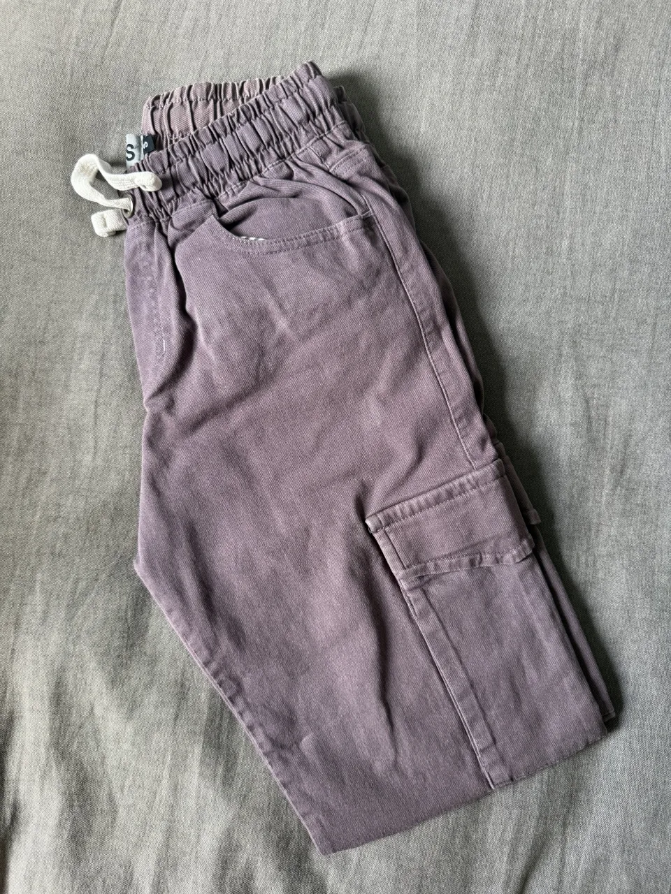 Pantalón cargo de algodón color lila, con cintura elastizada y cordón. Tiene bolsillos cargo a los costados y un corte moderno.