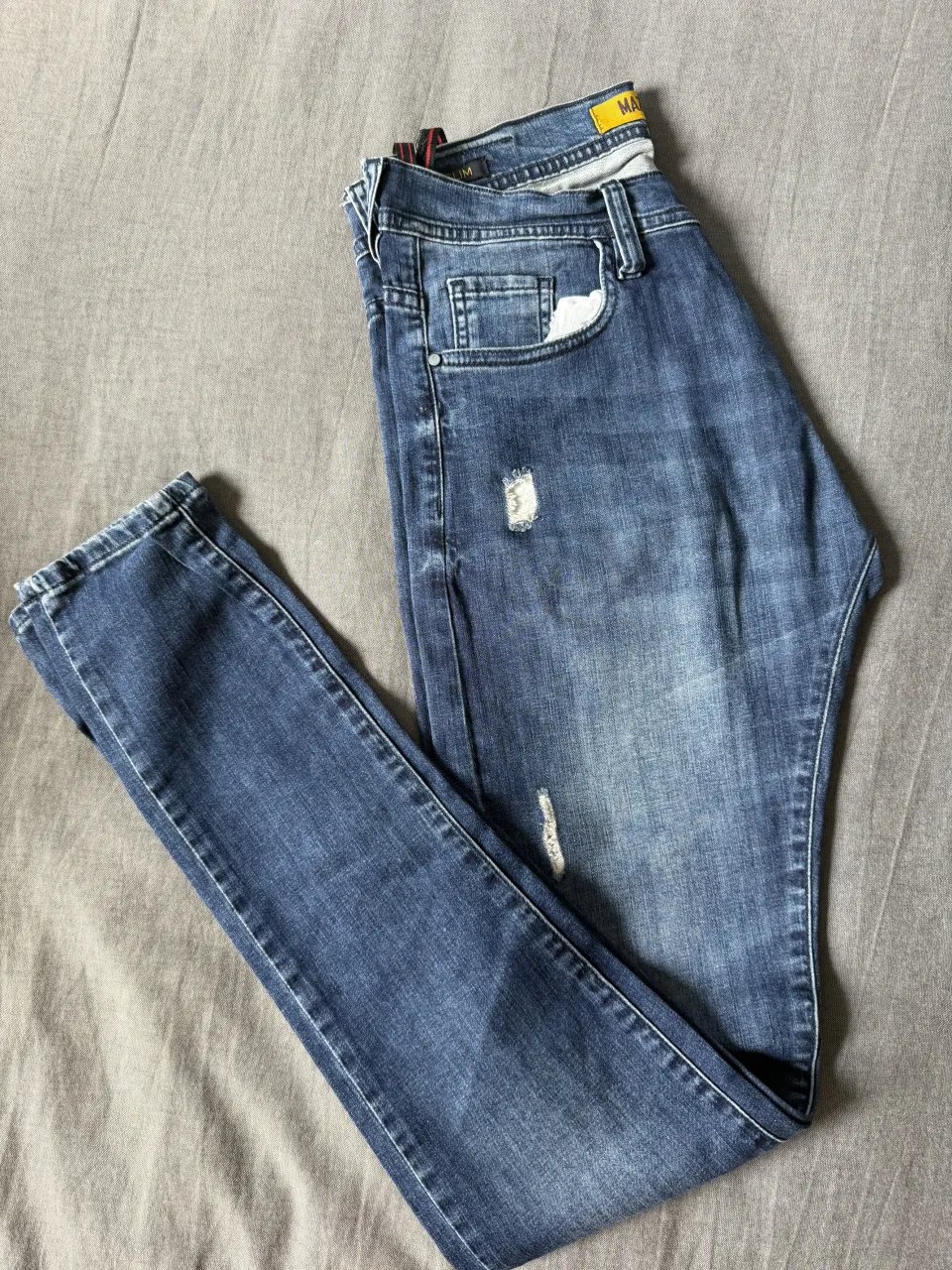 Jeans de corte slim, tiro medio, con detalles de roturas y desgastes que le dan un toque moderno y canchero. Perfectos para un look casual y relajado.