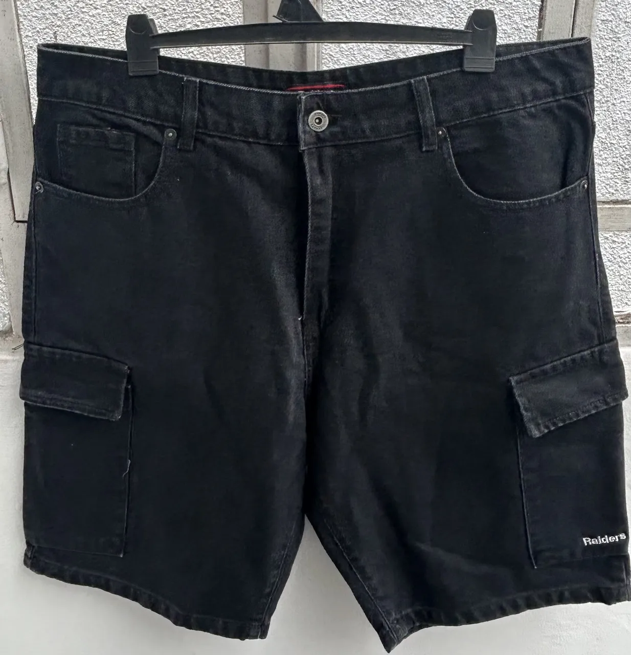 Short de jean negro con bolsillos cargo y detalle de la marca Raiders. Ideal para un look casual y urbano.