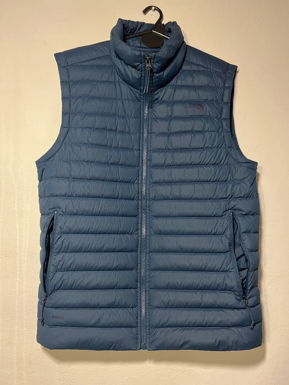 Chaleco acolchado azul para hombre, ideal para el invierno. Cuenta con cierre completo, bolsillos laterales y el logo de la marca en el pecho. Perfecto para un look casual y abrigado.