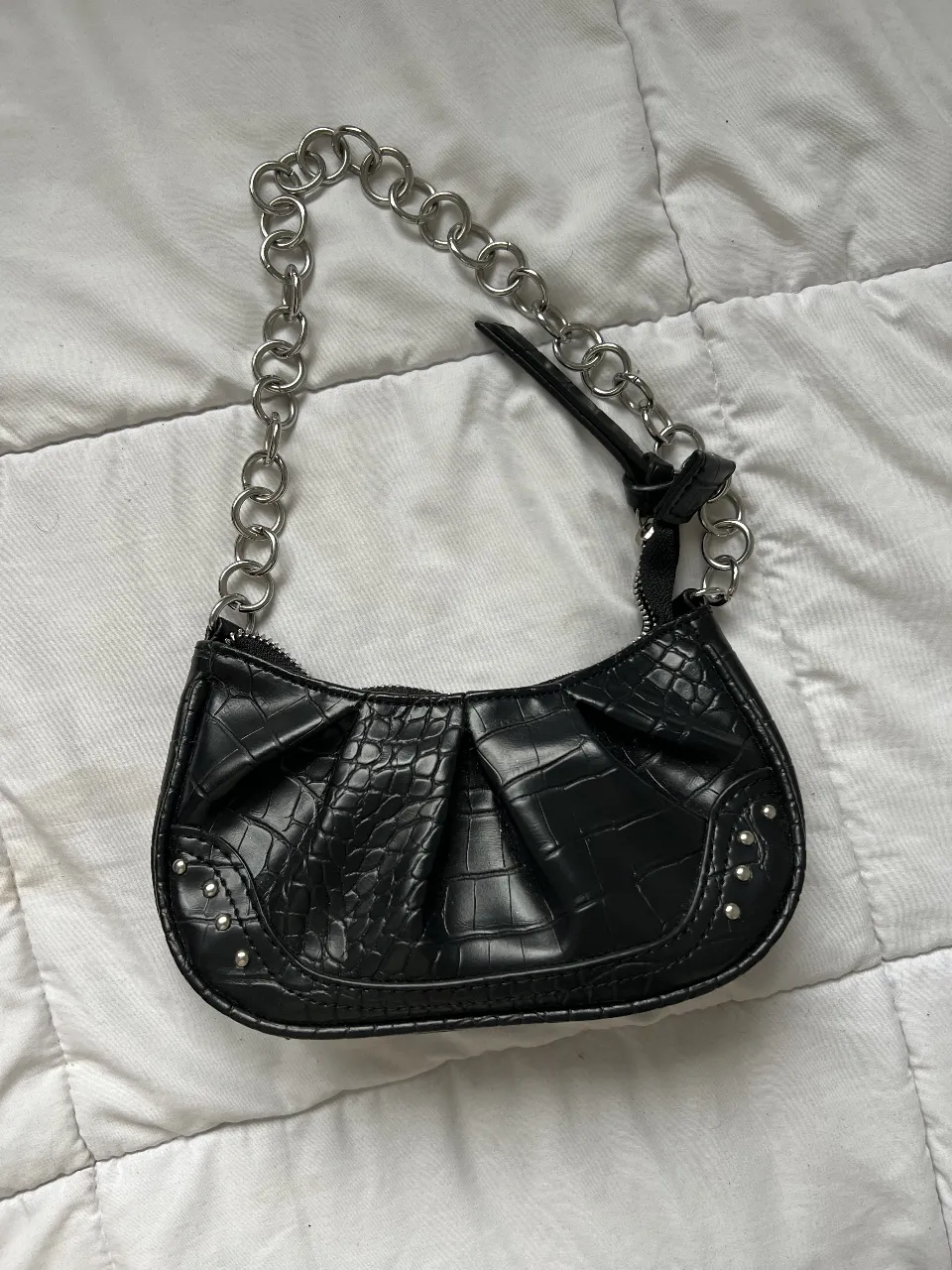 Cartera de hombro baguette negra con textura de cocodrilo y cadena plateada. Ideal para un look Y2K.