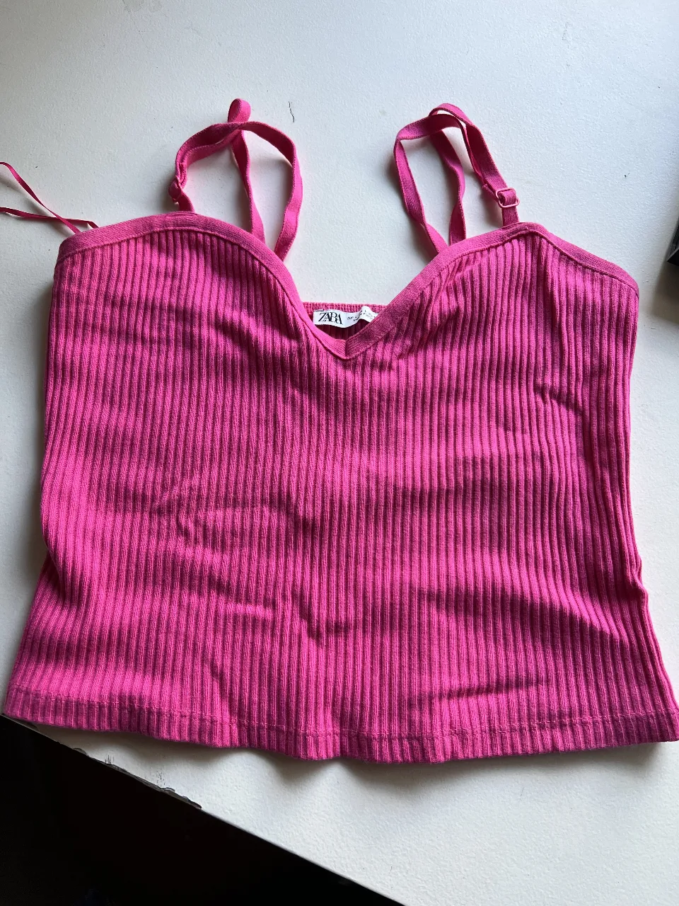 Top de mujer de tejido acanalado en color rosa, con escote en V y tirantes finos ajustables. Ideal para un look casual y moderno.
