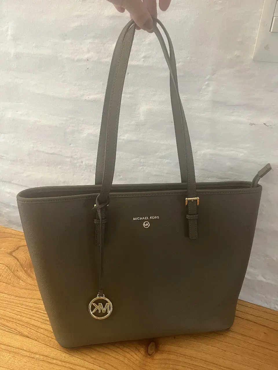 Cartera tote bag de cuero sintético color gris, con logo de la marca Michael Kors en dorado. Ideal para llevar todo lo necesario con estilo.