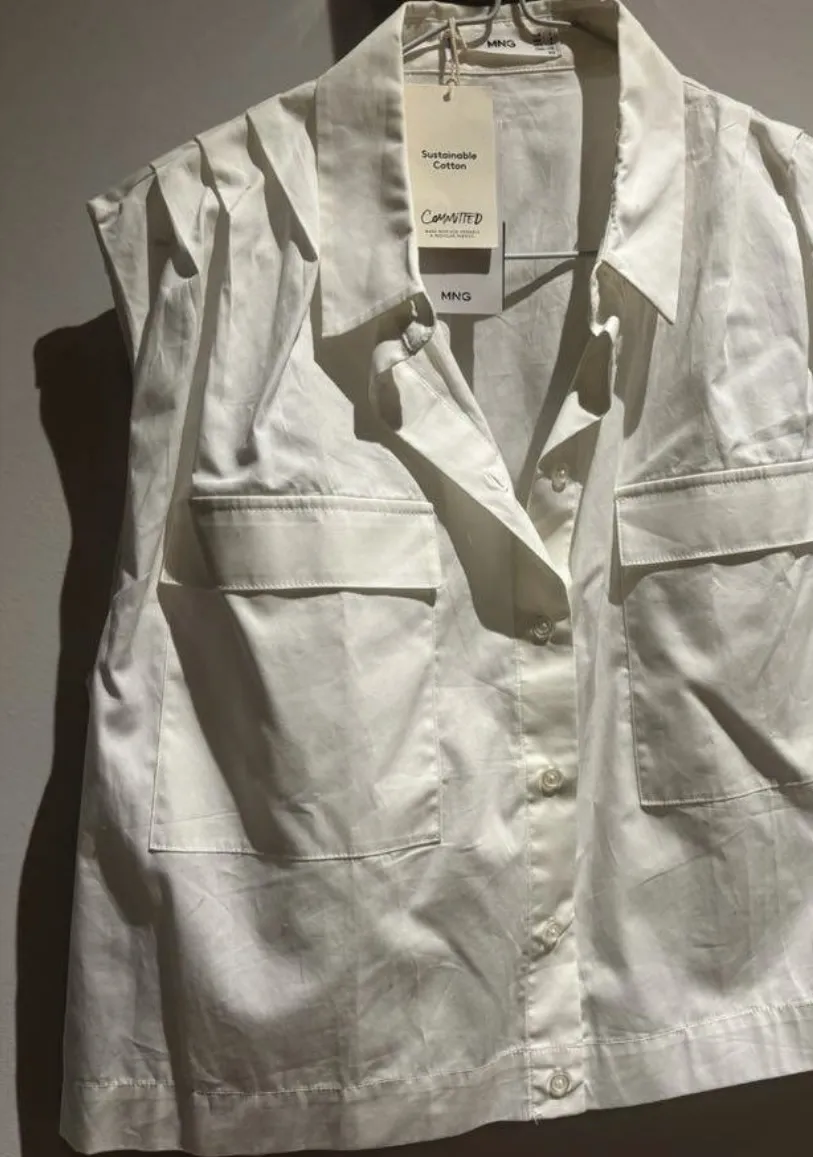 Camisa de mujer manga corta con dos bolsillos delanteros. Confeccionada en algodón sustentable, ideal para un look casual y fresco. Perfecta para combinar con jeans o pantalones de vestir.