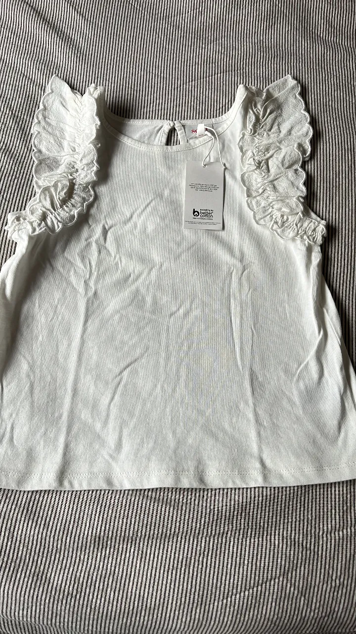 Blusa blanca de niña con volados en las mangas. Ideal para un look fresco y cómodo.