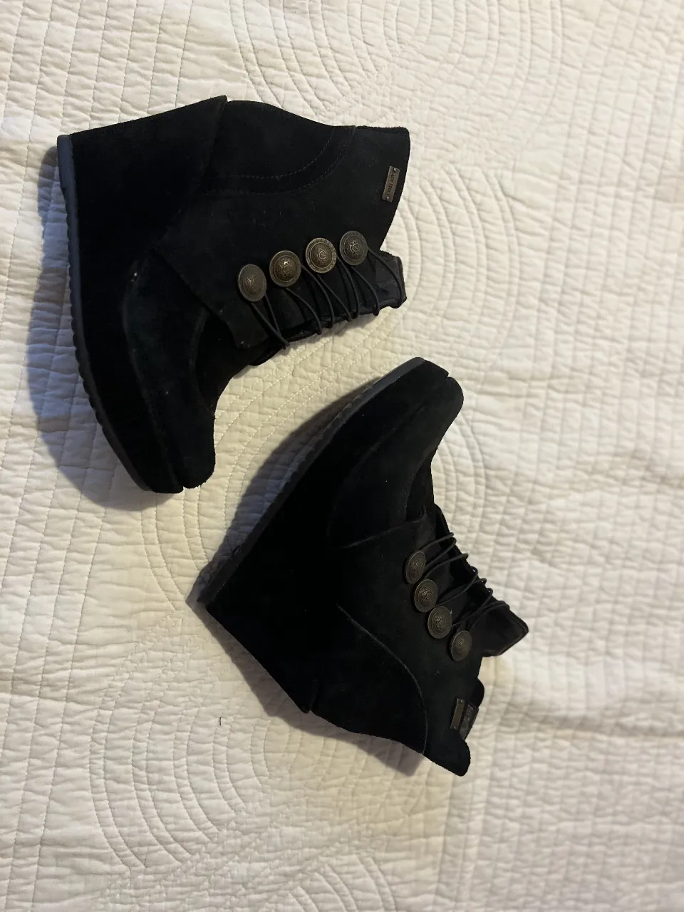Botines de gamuza negra con cuña y detalles de botones. Ideales para un look casual y cómodo.