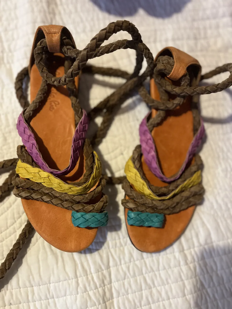 Sandalias artesanales de cuero con tiras trenzadas y detalles en colores vibrantes. Ideales para un look bohemio y cómodo en verano.