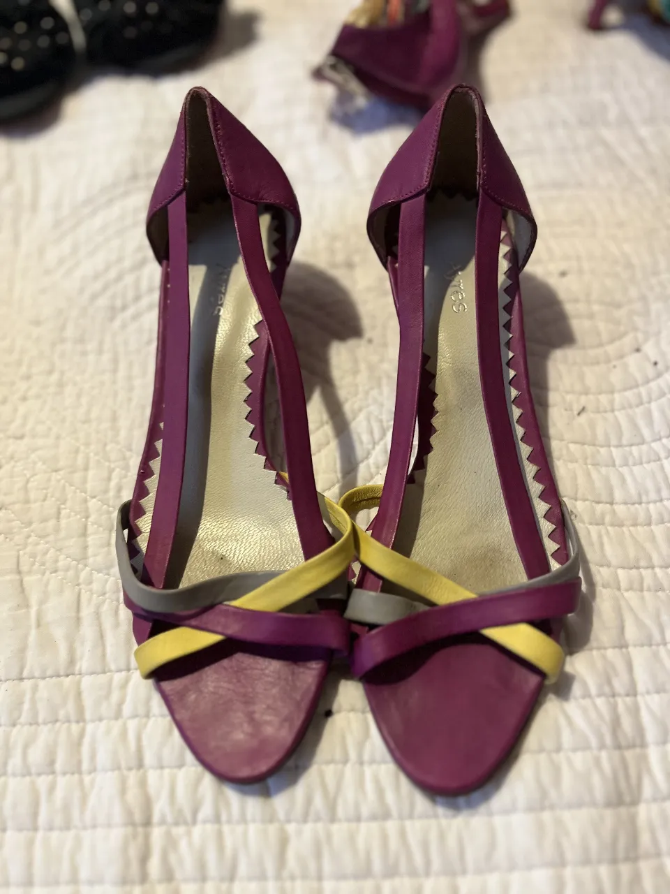 Sandalias de mujer color violeta con detalles en amarillo y gris. Diseño elegante con tiras cruzadas y detalles dentados. Ideales para un look de verano.