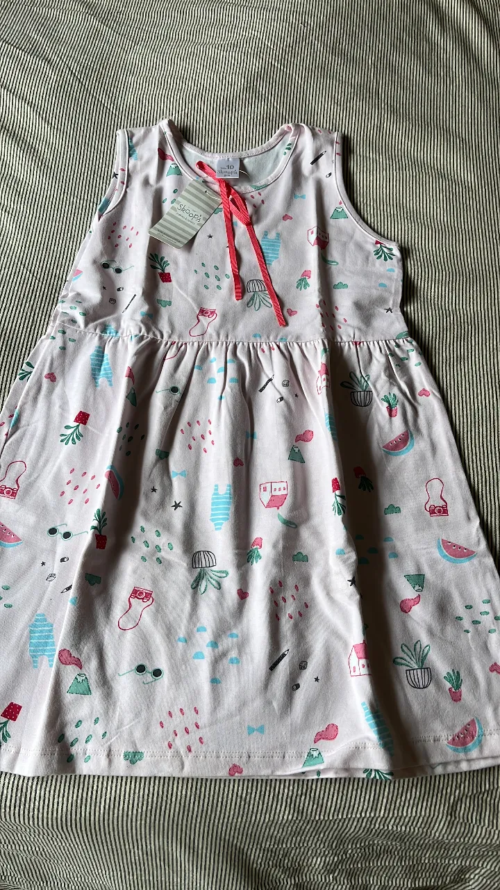 Vestido de niña con estampado de motivos infantiles. Diseño sin mangas, con lazo en el cuello y falda con vuelo. Ideal para el verano.