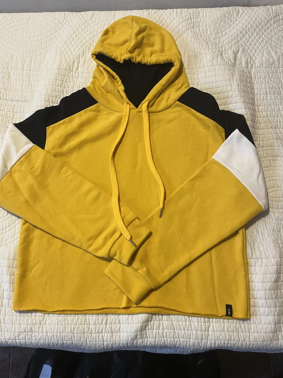 Buzo canguro unisex, color amarillo con detalles en negro y blanco. Ideal para un look casual y cómodo.