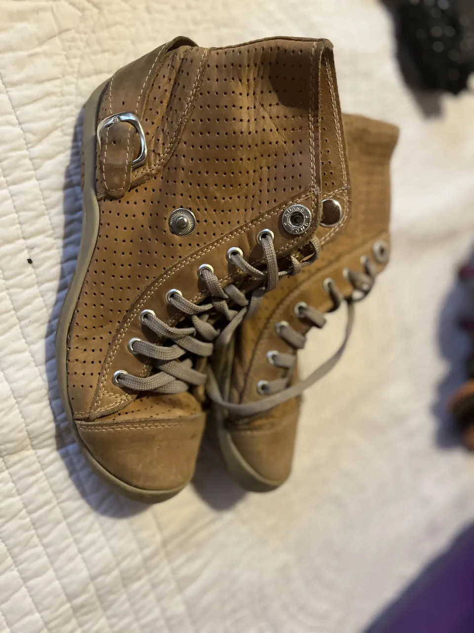 Botines de cuero marrón con detalles perforados y cierre con hebilla. Ideales para un look casual y cómodo.