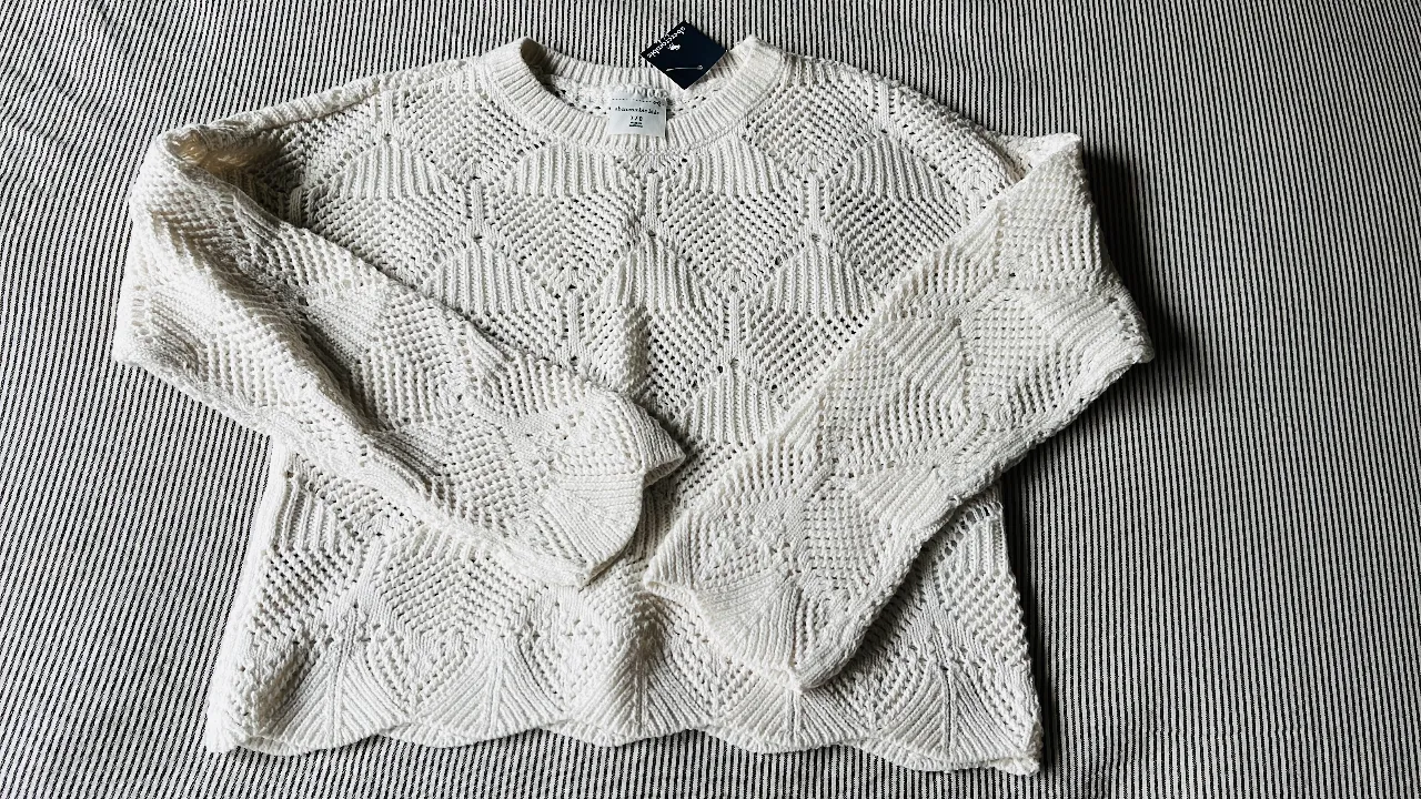 Sweater largo tejido en color blanco, con diseño calado y mangas amplias. Ideal para un look casual y cómodo.