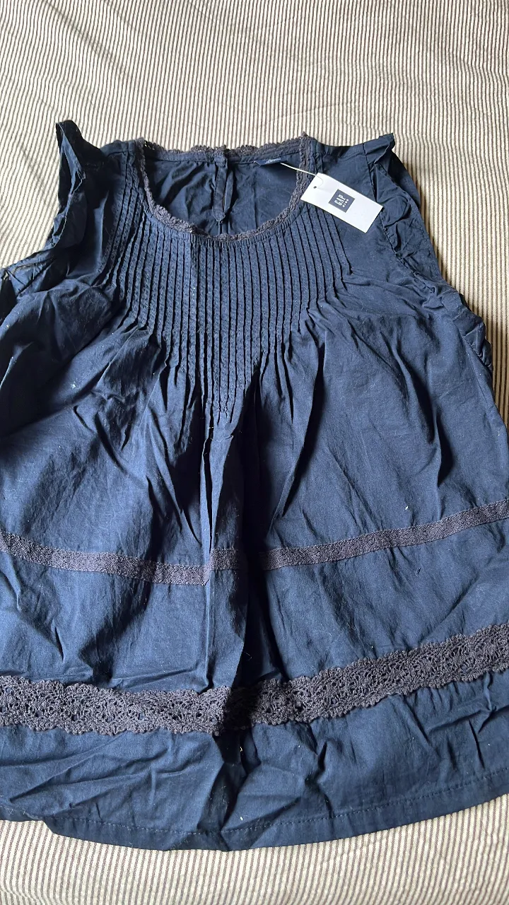 Blusa de algodón azul oscuro con detalles de encaje y plisados en el frente. Ideal para un look fresco y femenino.