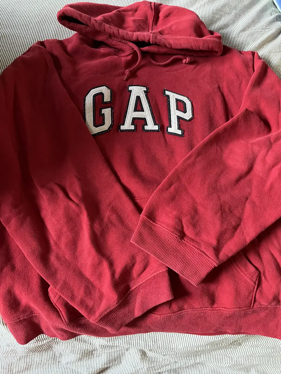 Buzo canguro rojo de la marca GAP, con el logo de la marca en blanco en el frente. Talle M, ideal para un look casual y cómodo.