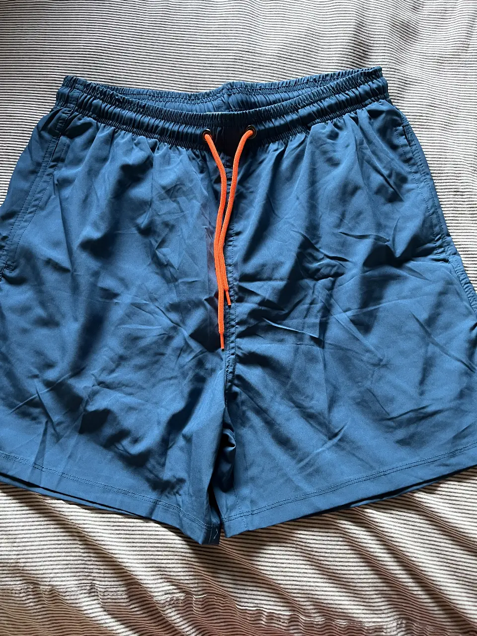 Short de baño azul para hombre, con cordón naranja en la cintura. Ideal para la playa o pileta.