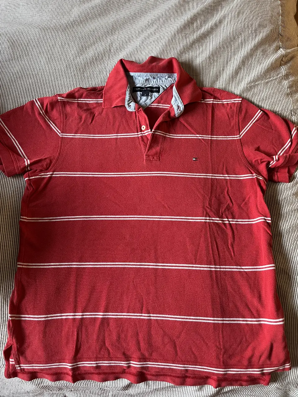 Remera polo Tommy Hilfiger roja con rayas blancas horizontales. Talle M. Ideal para un look casual y deportivo.
