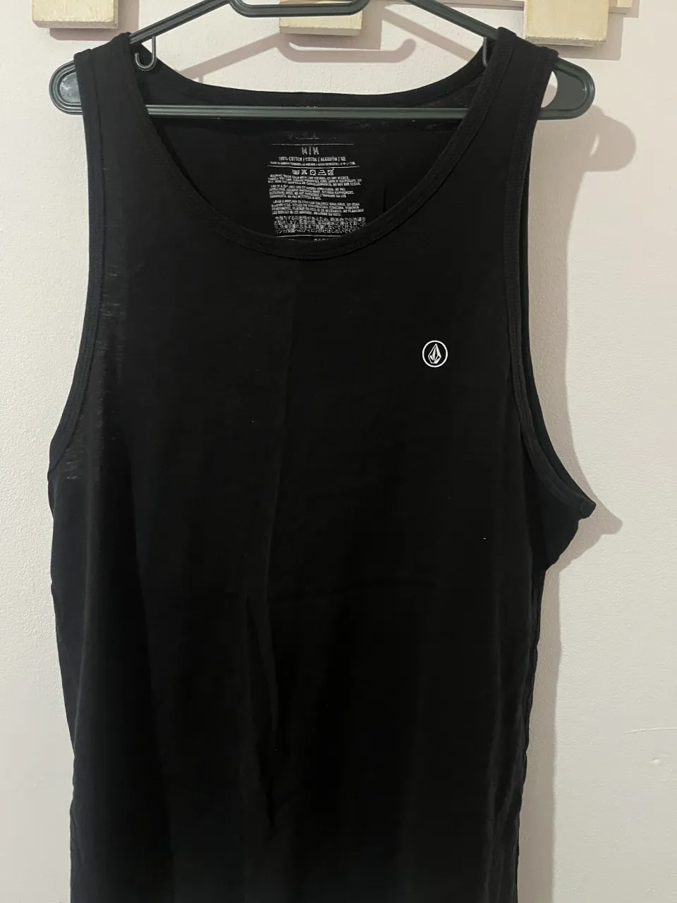 Musculosa negra lisa con logo pequeño de la marca en el frente.