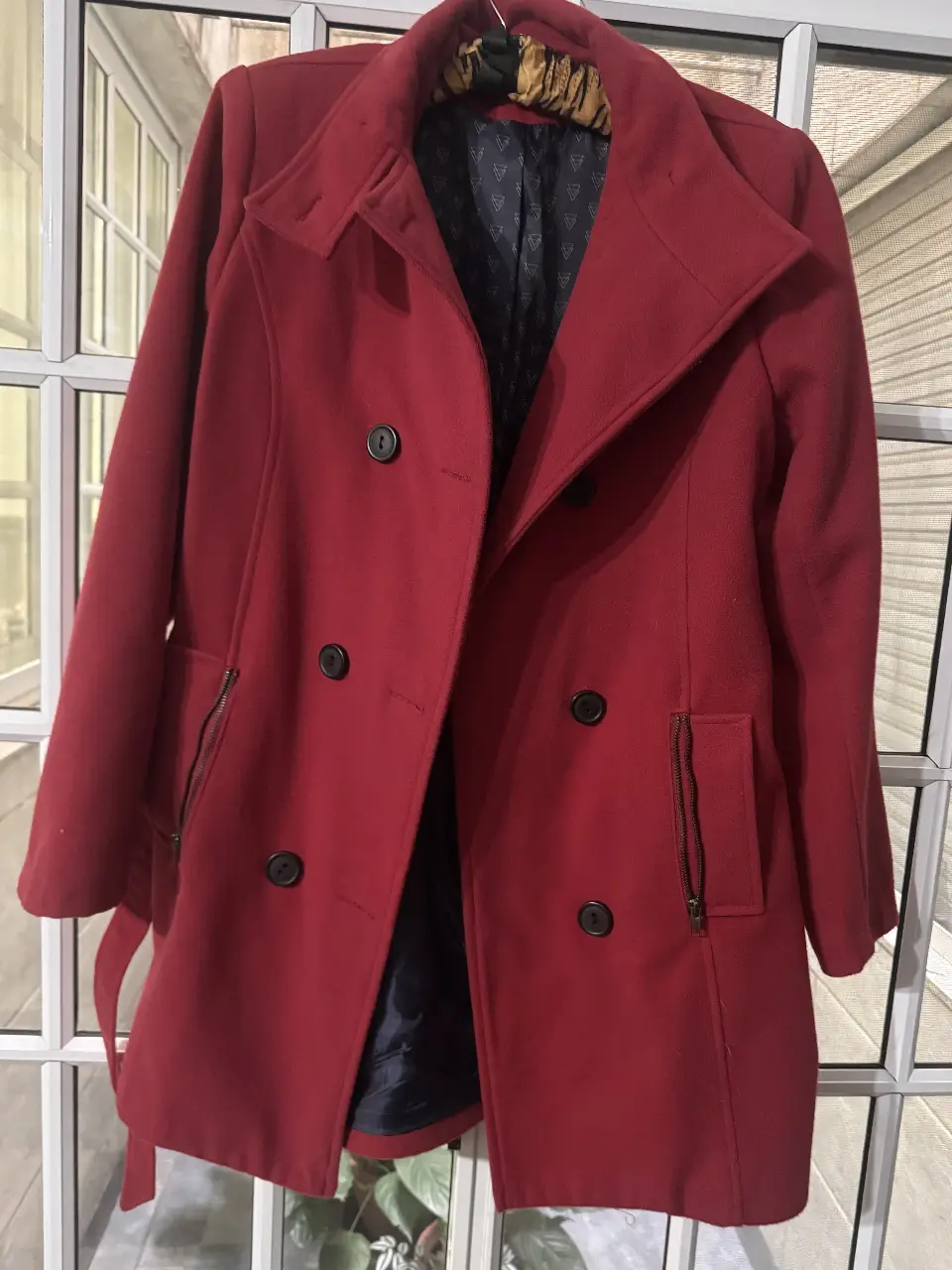 Tapado rojo de paño, con corte clásico y elegante. Posee dos bolsillos con cierre y cinturón para ajustar la cintura. Ideal para un look sofisticado y abrigado en invierno.