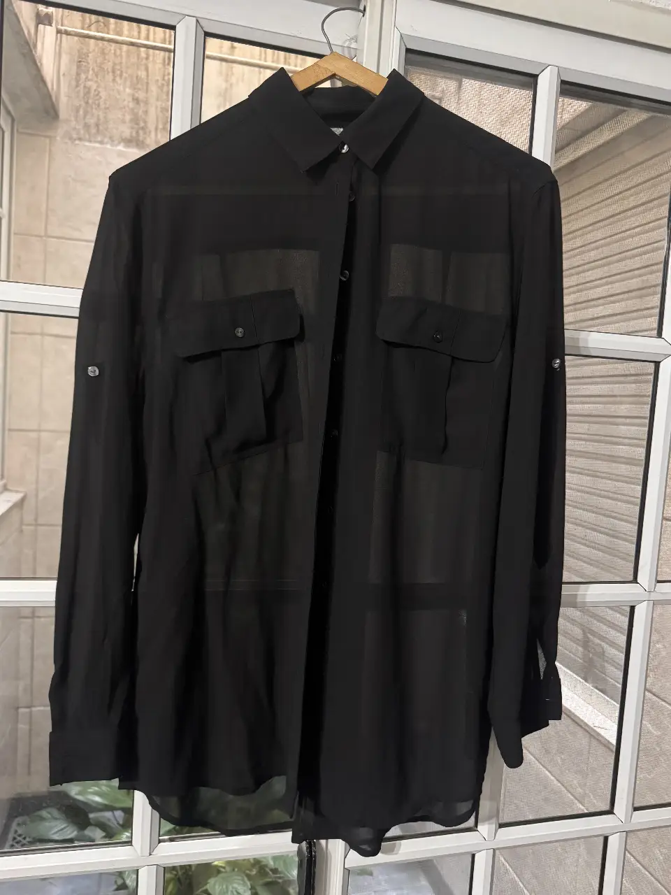 Camisa negra de mujer, con mangas largas y bolsillos en el pecho. Ideal para un look elegante y versátil.
