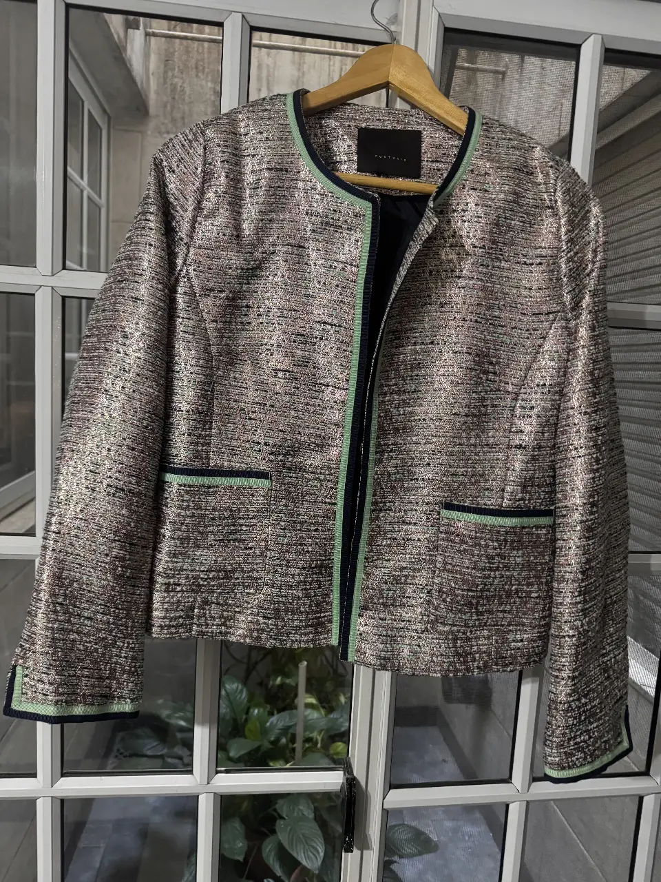 Elegante blazer de mujer de la marca Ports Said, con un diseño texturizado en tonos plateados y detalles en verde. Ideal para un look sofisticado y moderno.