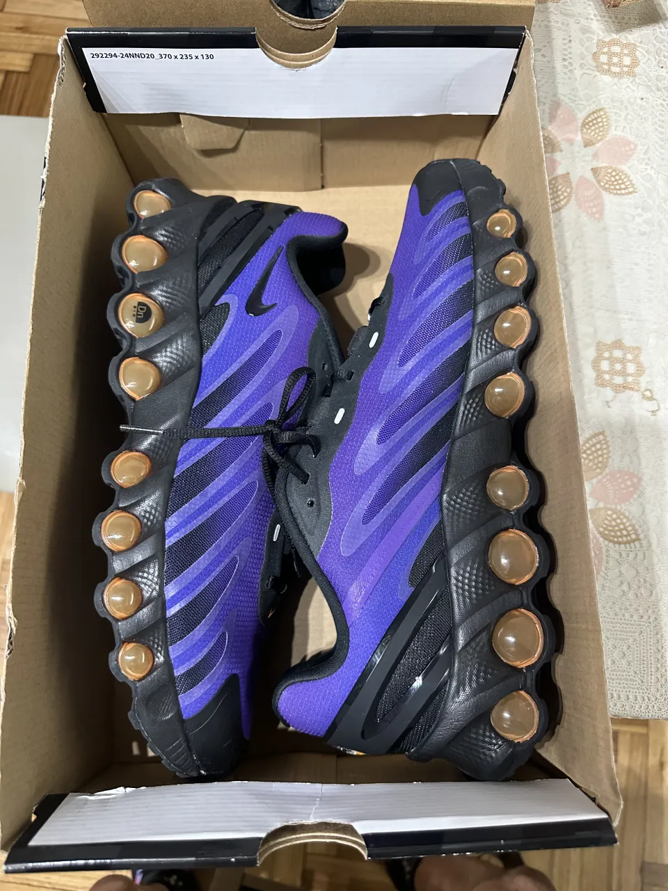 Zapatillas deportivas Nike Air Max TN, color violeta y negro con detalles en naranja. Cordones negros.