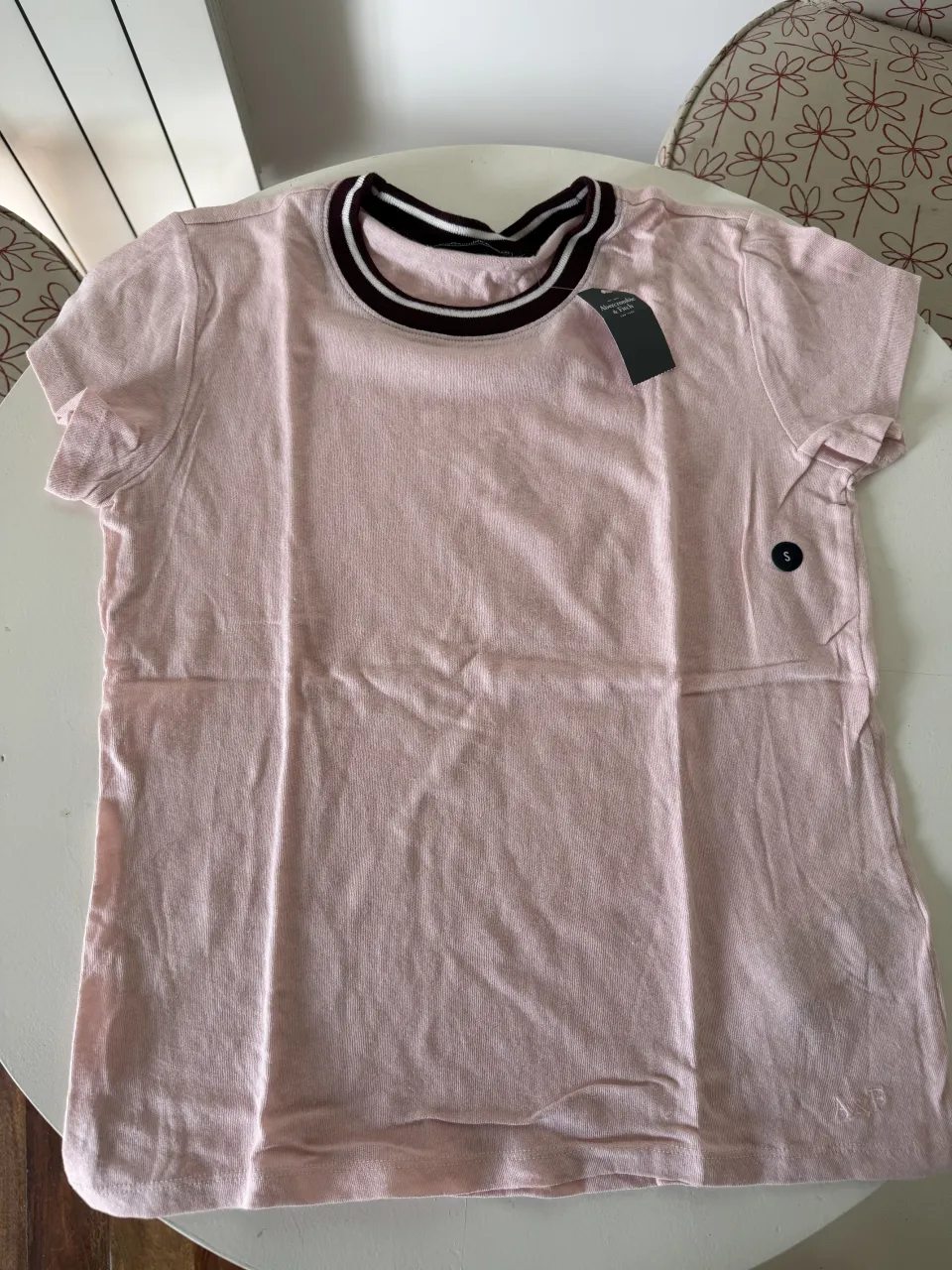 Remera rosa de algodón con cuello redondo y detalles en negro y blanco. Ideal para un look casual y cómodo.