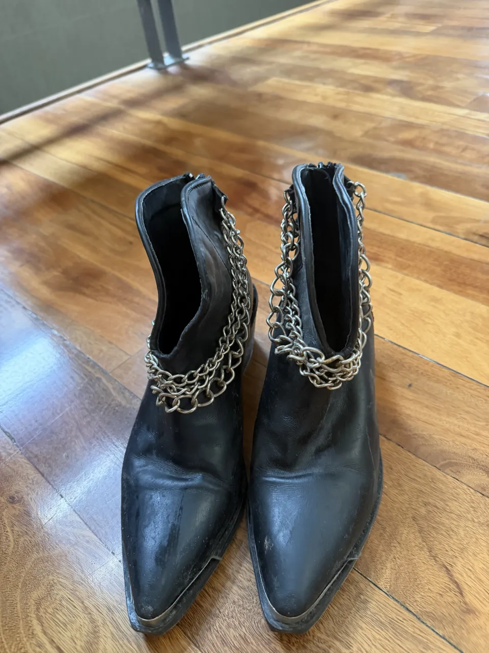 Botas negras de cuero con cadenas plateadas alrededor del cuello.