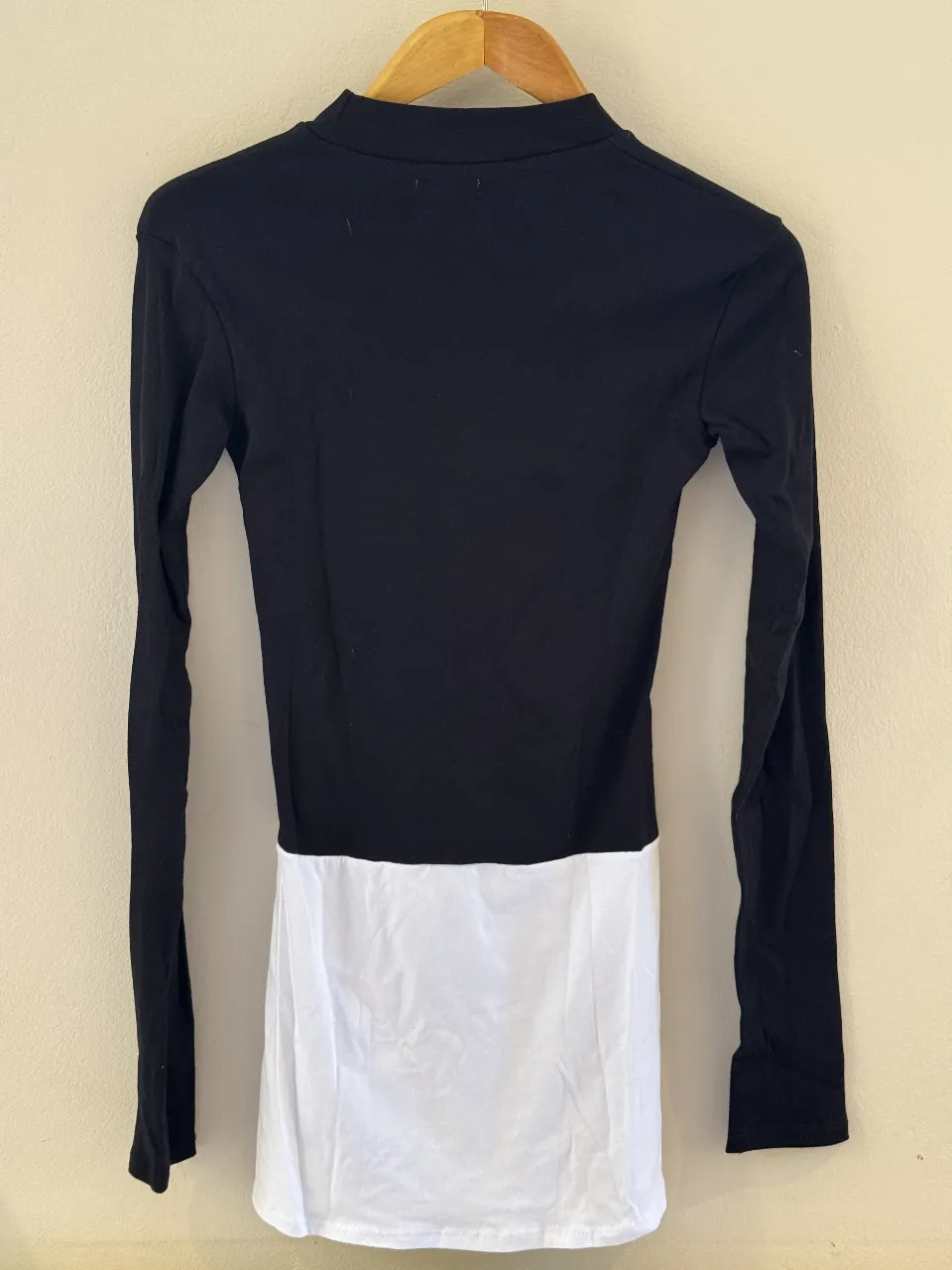 Remera manga larga con cuello alto, combinada en negro y blanco. Diseño moderno y versátil, ideal para cualquier ocasión.