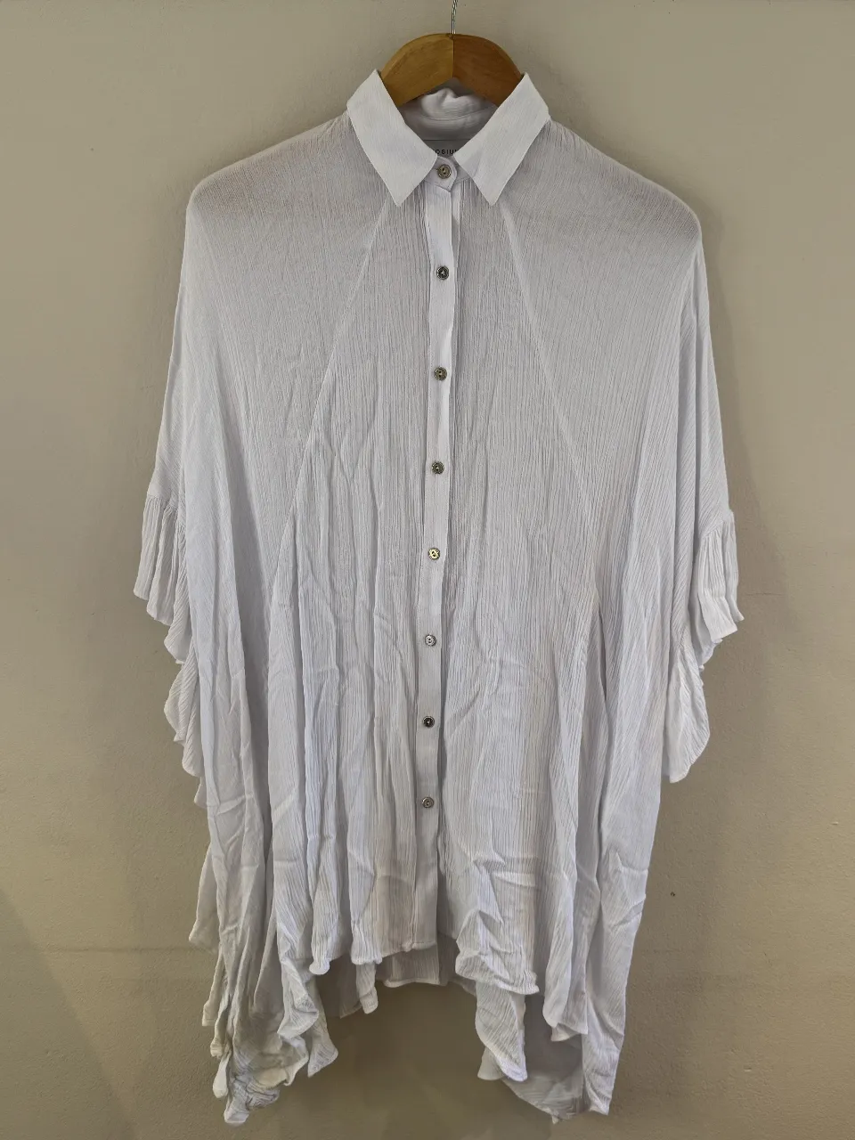 Camisa blanca de tela liviana, con cuello mao y botones al frente. Posee mangas amplias con volados y un corte asimétrico que le da un toque moderno y canchero. Ideal para un look relajado y chic.Es talle unico pero es mas un L