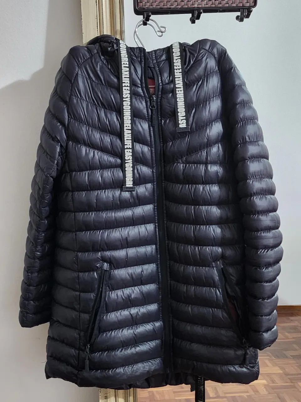 Campera acolchada negra con capucha. Tiene detalles de estampa en las tiras de la capucha y forro interior en color rojo. Ideal para días fríos y para un look casual.