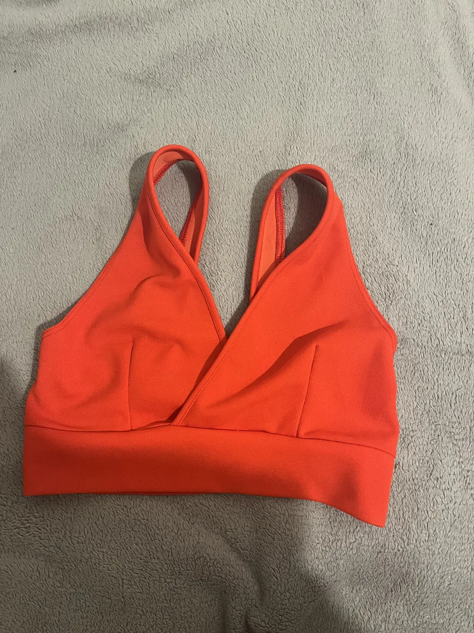 Top deportivo rojo con diseño cruzado en el frente. Ideal para actividades de bajo impacto.