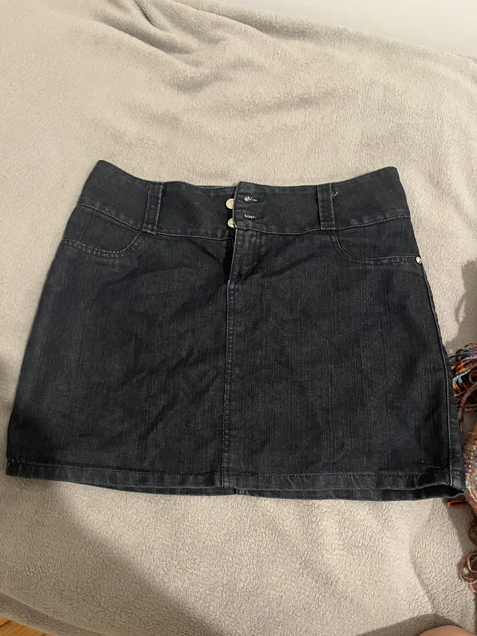 Minifalda de jean negra, con detalles de botones y bolsillos. Ideal para un look casual y versátil.