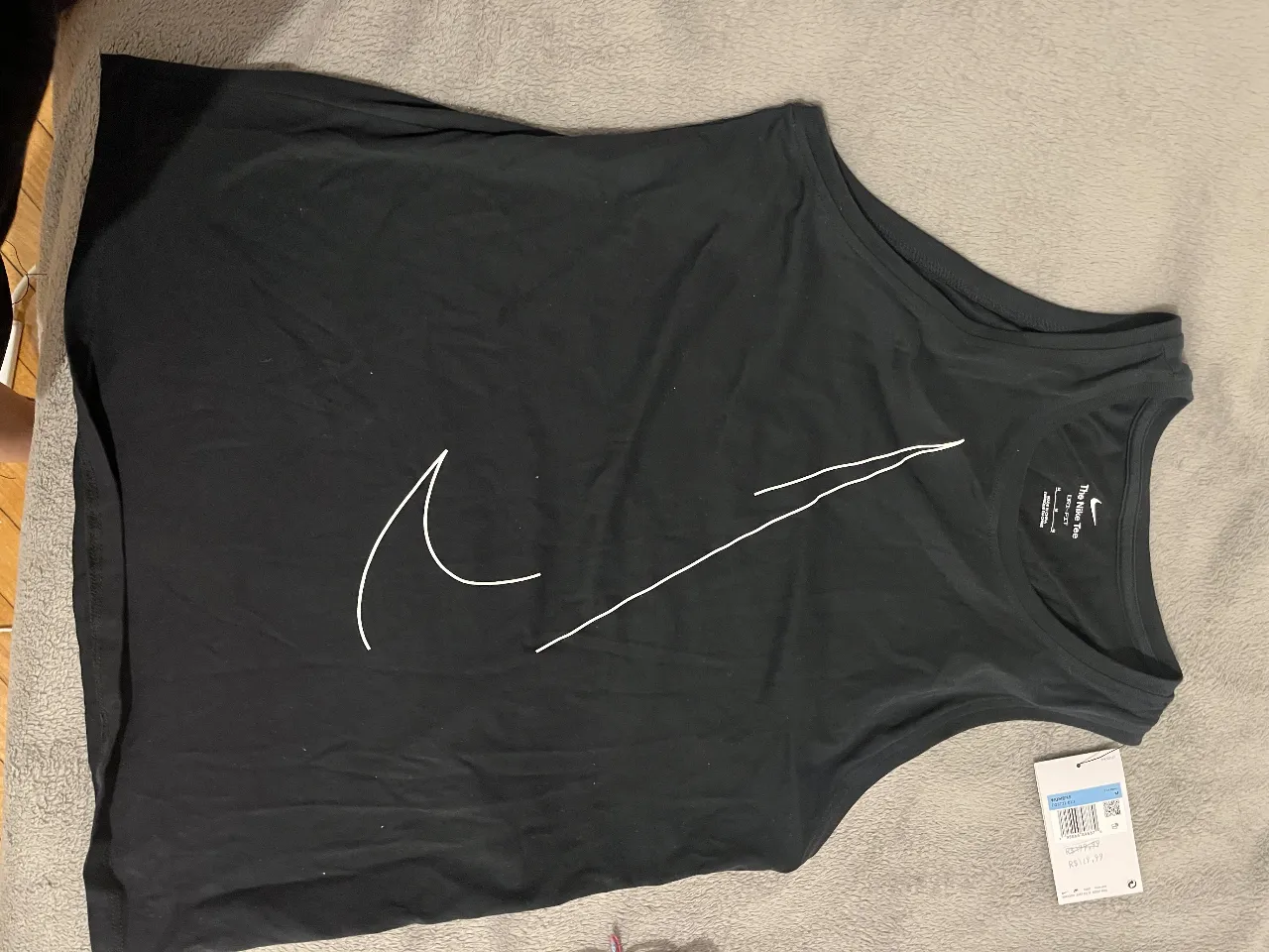 Musculosa deportiva Nike Dri-FIT para mujer, de color negro con el logo de la marca en blanco. Ideal para entrenamientos y actividades físicas.