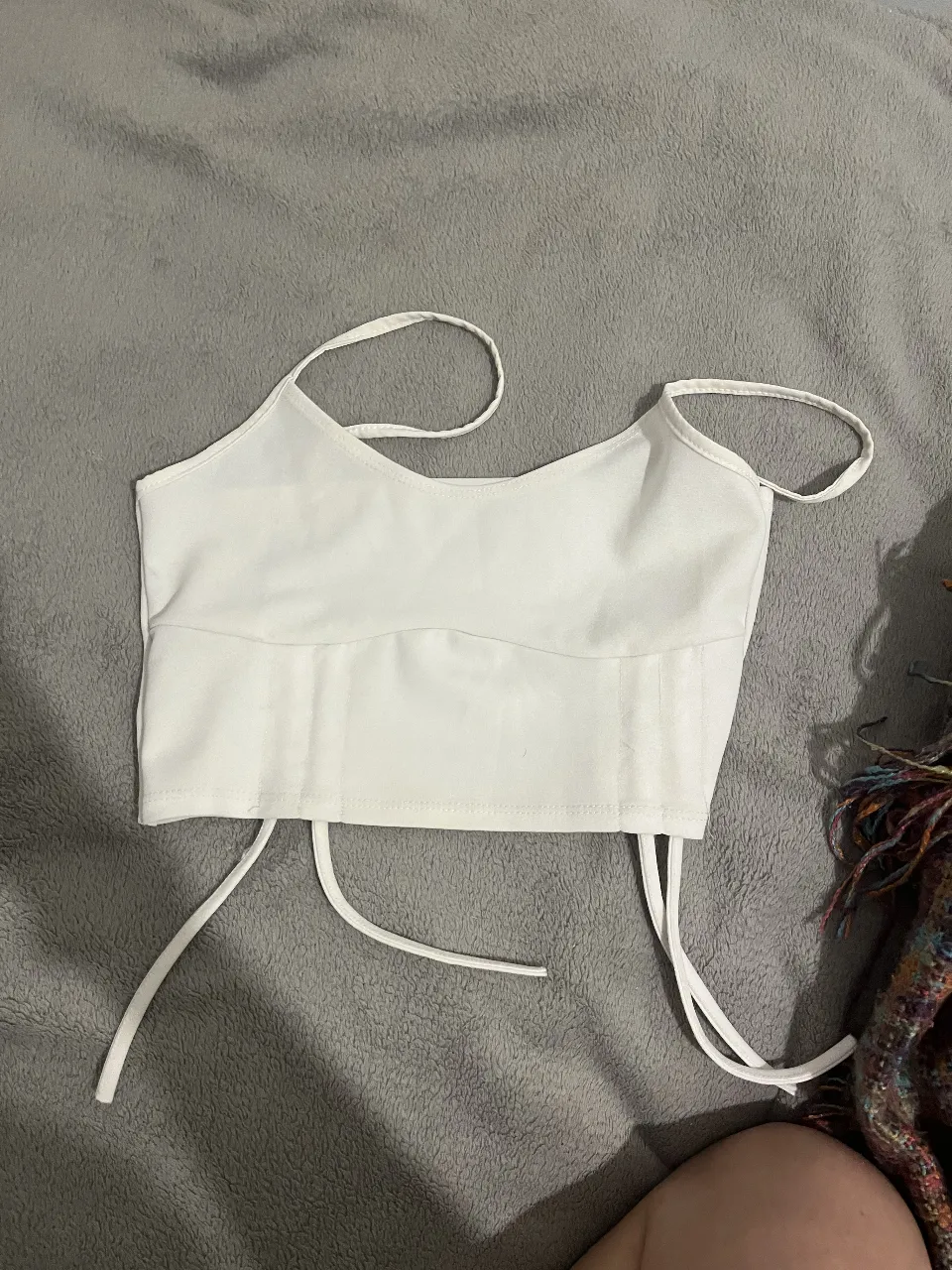 Top blanco con tiras finas y detalles de ajuste en la parte inferior. Ideal para un look moderno y fresco. Sin usos