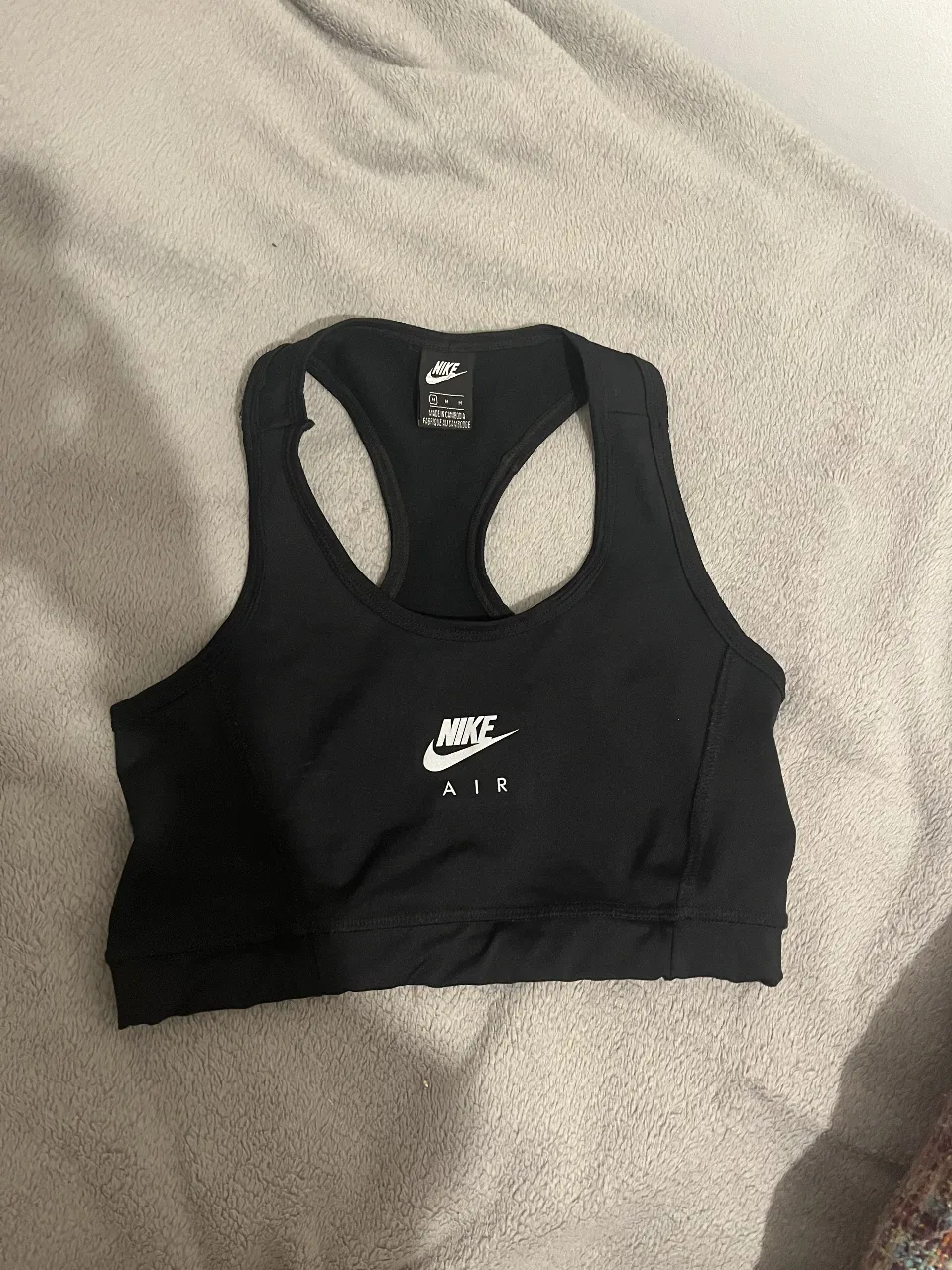 Top deportivo negro de la marca Nike, ideal para entrenamientos y actividades físicas. Diseño moderno y cómodo.