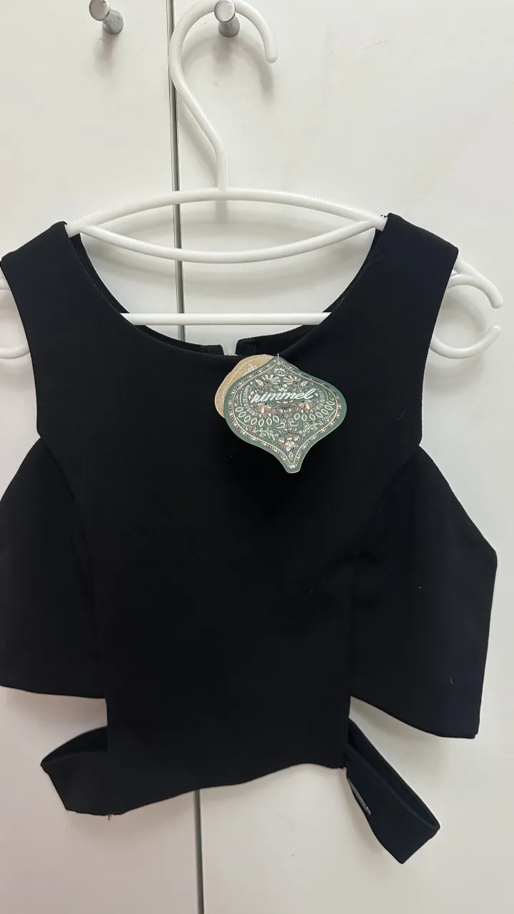 Top negro con recortes en la parte inferior y cierre en la espalda.