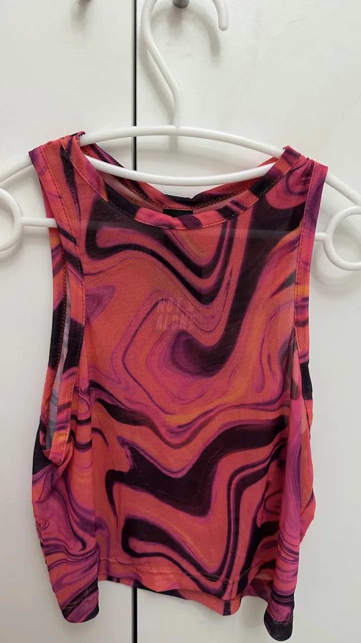 Top halter de tul con estampa psicodélica en tonos rosas, naranjas y negros. Ideal para utilizar con una remera blanca o negra por debajo.