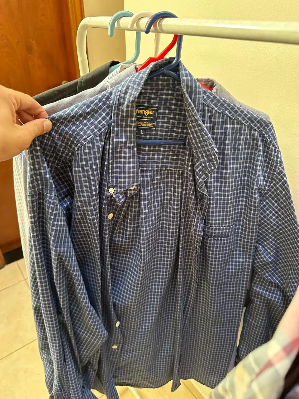 Camisa a cuadros azul y blanco de hombre, manga larga, con bolsillo en el pecho y etiqueta de la marca Wrangler. Ideal para un look casual.