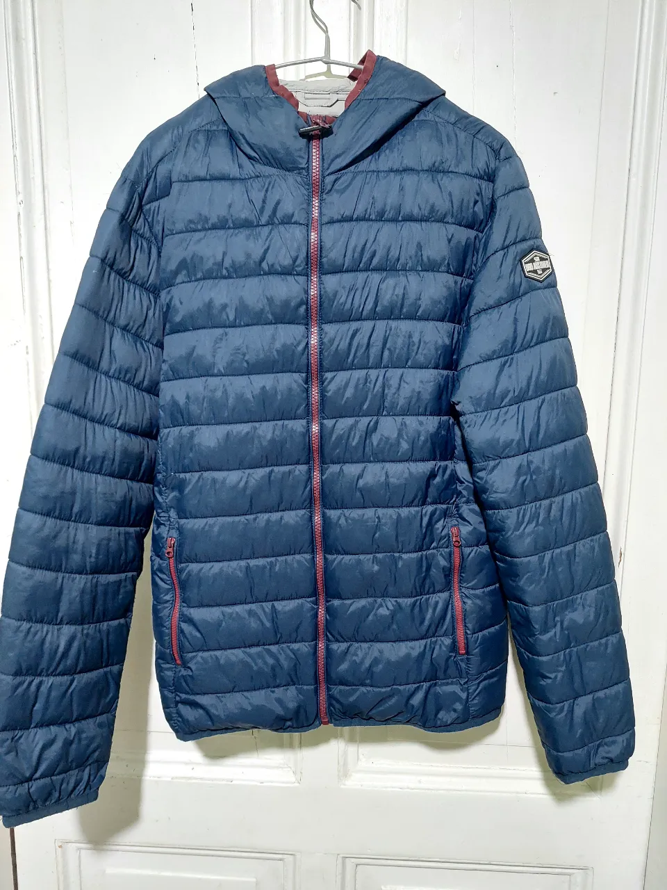 Campera Doo Australia azul marino con capucha, cierre y bolsillos. Ideal para el invierno, con un diseño acolchado y detalles en rojo. Talle Small.