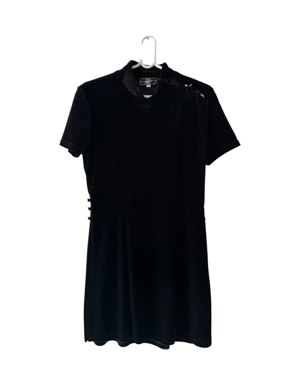 Vestido mini negro simil terciopelo con cuello alto y detalles de botones forrados en un hombro y en los laterales. Ideal para una salida nocturna o evento especial. tiene 2 tajos laterales que llegan a la cintura, para usar como detalle arriba de un vestido, pollera, palazzo.