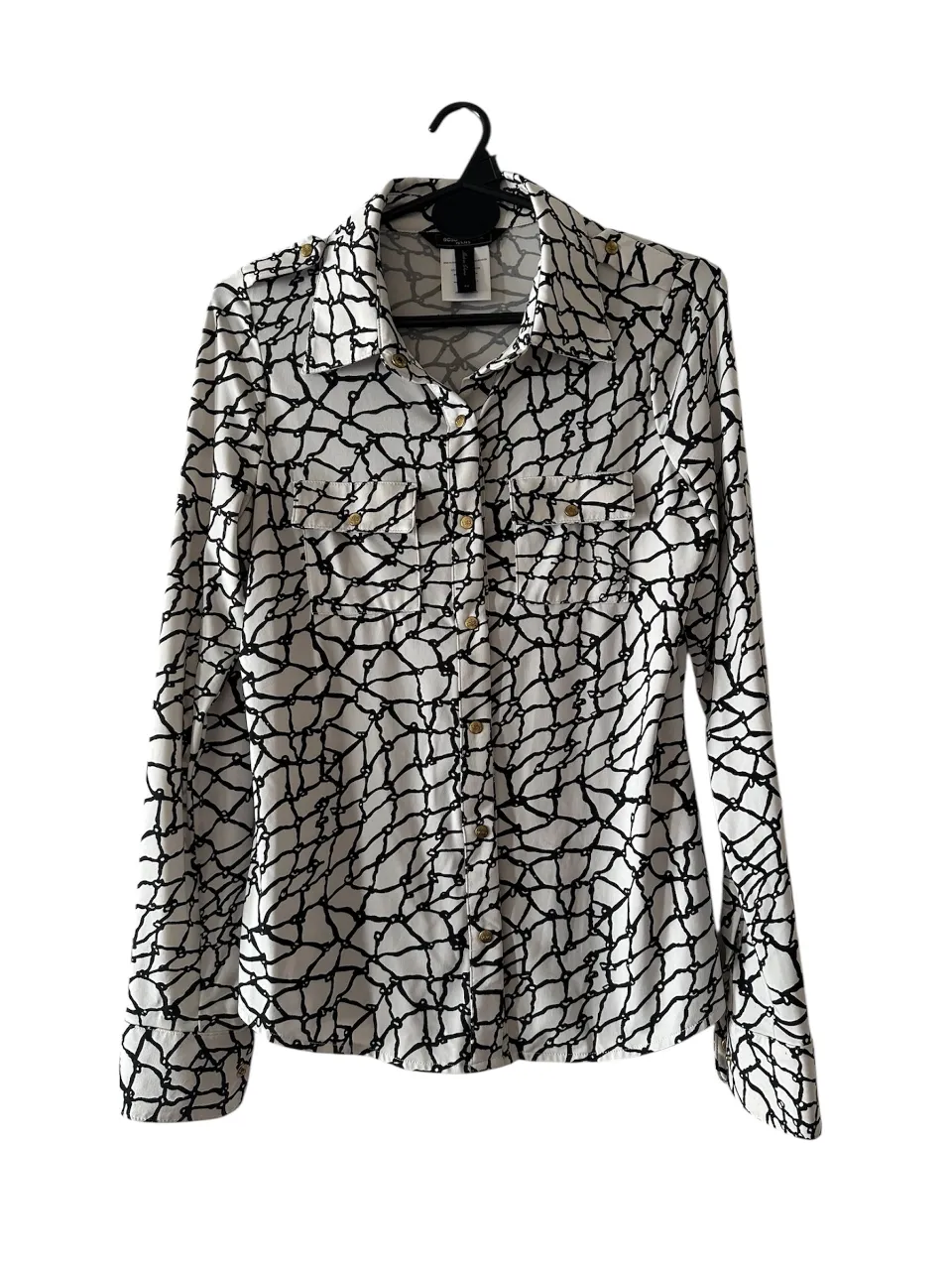Camisa de mujer con estampado de red en blanco y negro. De la marca BCBGMAXAZRIA, con botones clips dorados y mangas largas. con 2 bolsillos aplicados a solapados con botones. Ideal para un look elegante y moderno. en seda fría.
medidas: hombros: 35; axilas:44; largo: 61