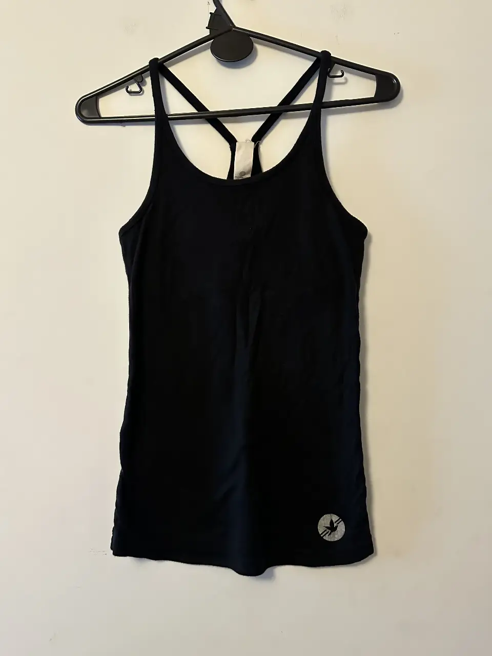 Musculosa deportiva negra con espalda cruzada, forro en busto y logo en la parte inferior. Ideal para entrenamientos. medidas: axilas:32cm.-. largo:65cm