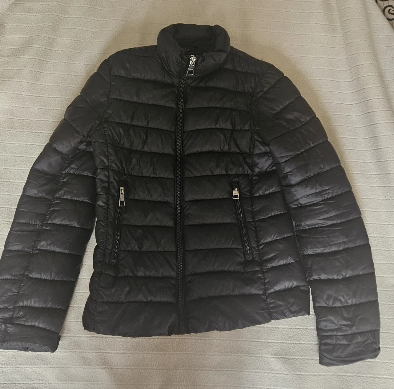 Campera negra acolchada de mujer, con cierre y bolsillos. Marca MNG. Ideal para el invierno.