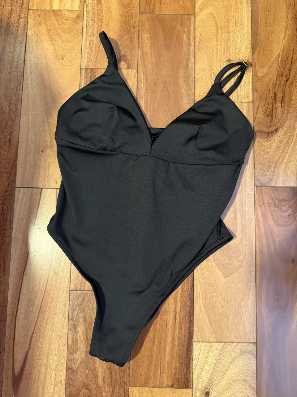 Traje de baño negro, tipo body, con breteles finos y escote pronunciado en V.