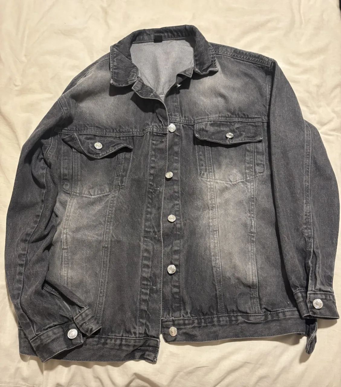 Campera de jean gris con botones al frente y en los puños. Posee dos bolsillos con tapa en el frente.