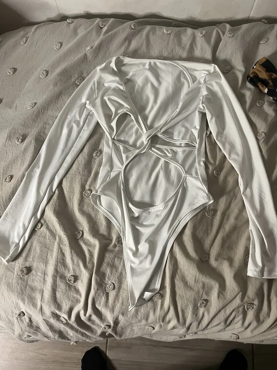 Body blanco de manga larga con diseño cut out y detalle de nudo en la parte delantera. Ideal para un look moderno y sofisticado.