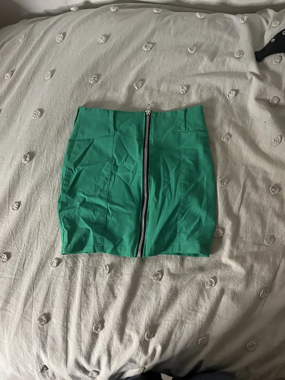 Minifalda verde con cierre frontal. Ideal para un look moderno y audaz.