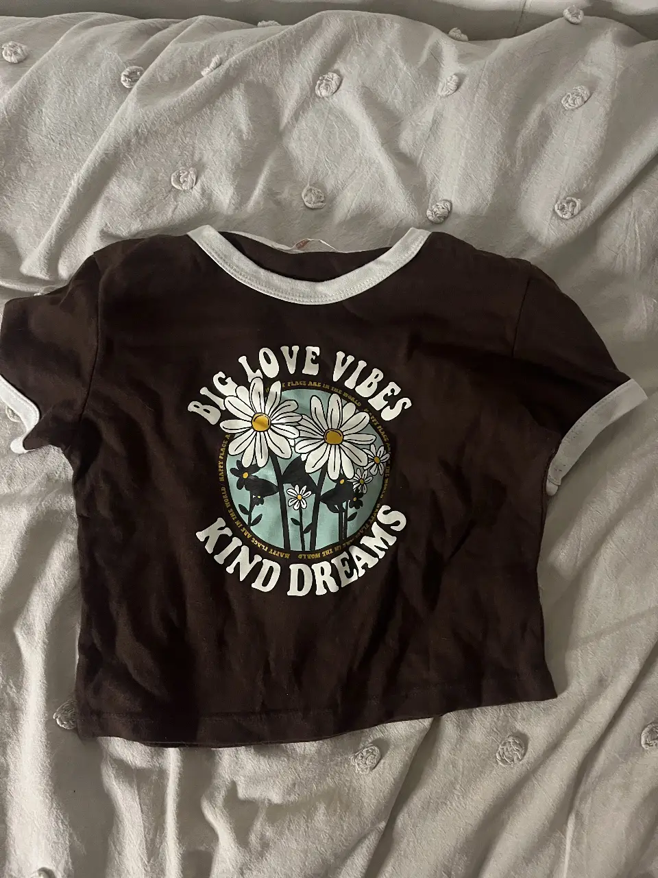 Remera crop de algodón marrón con estampado "Big Love Vibes Kind Dreams" y detalles en blanco. Ideal para un look casual y con onda.