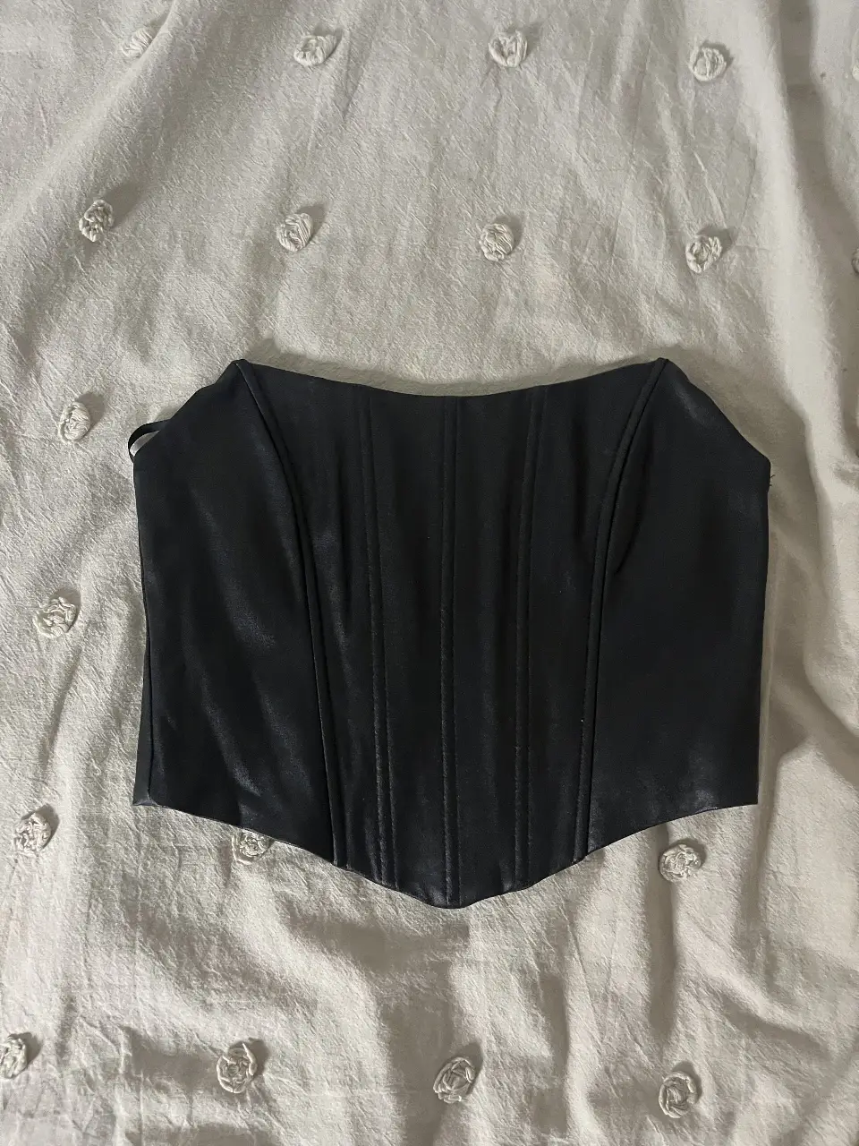 Top corset negro de la marca Windsor, ideal para una salida o fiesta. Confeccionado en material similar al cuero, este top sin mangas es perfecto para un look elegante y moderno. Talle S.